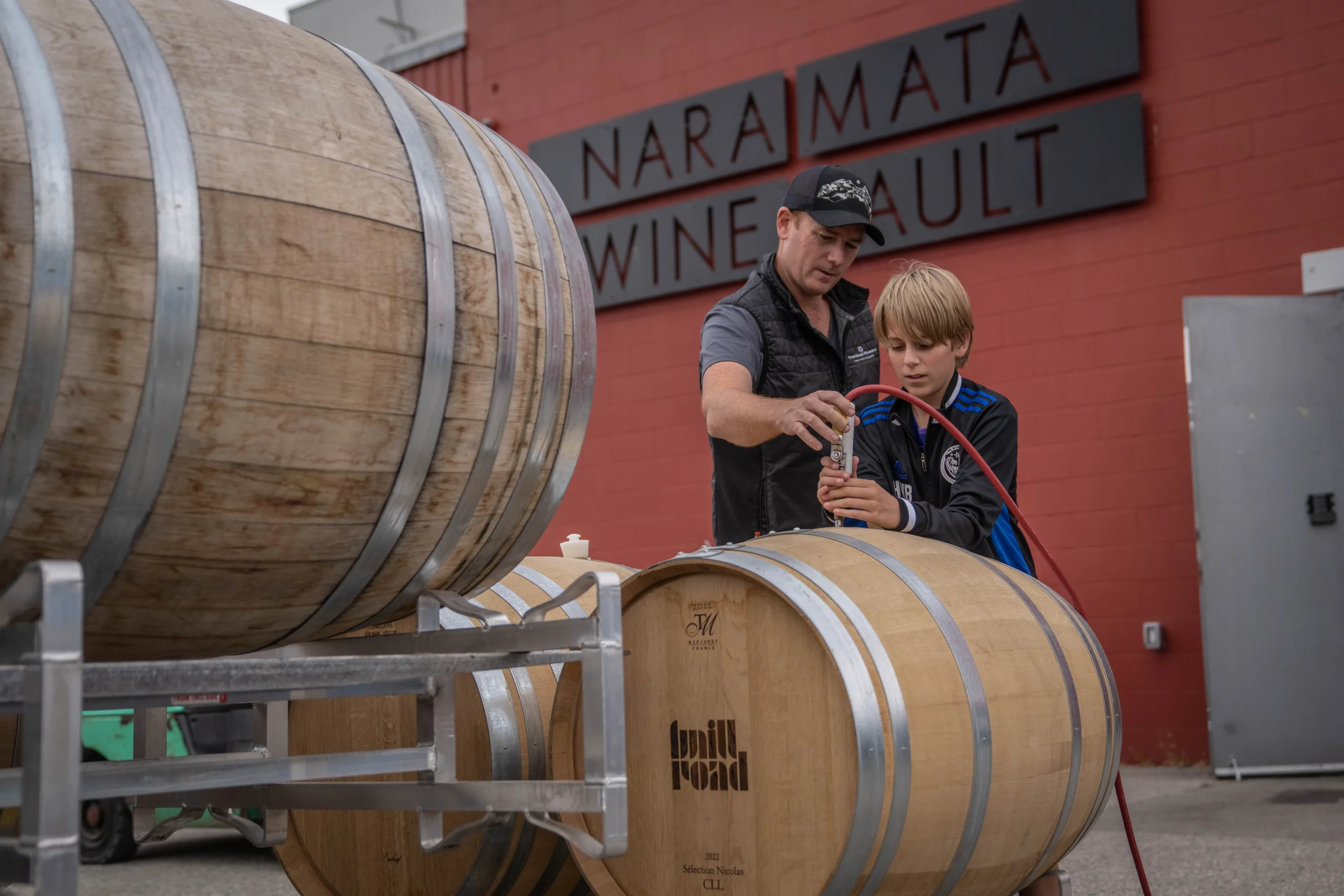 Ben and his son filling a wine barrel together